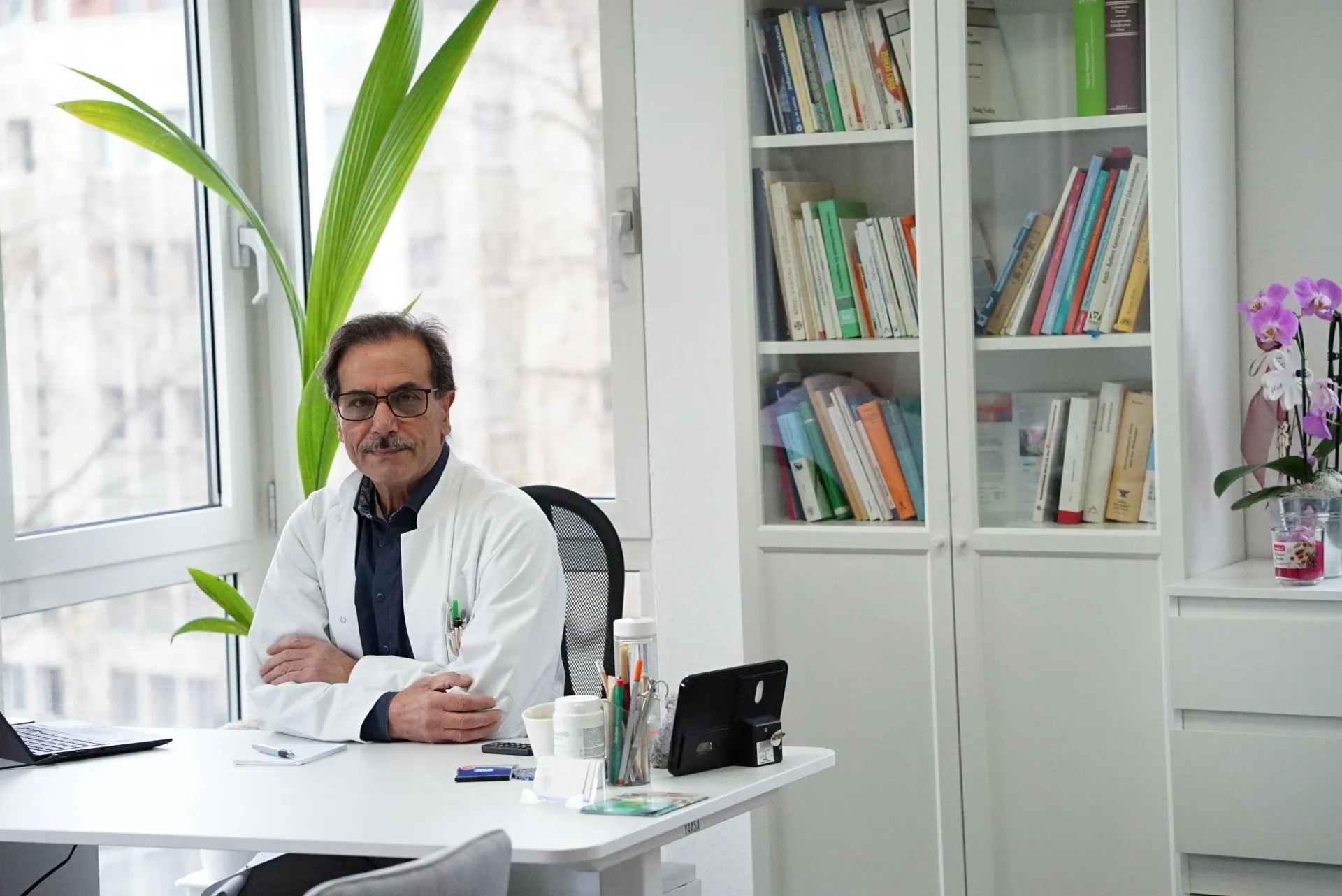 Yaşar Kes an seinem Schreibtisch, umgeben von Fachliteratur und Pflanzen